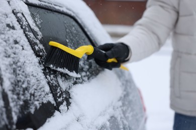 Photo of Man cleaning snow from car outdoors, closeup