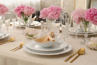 Stylish table setting with beautiful peonies and fabric napkin indoors