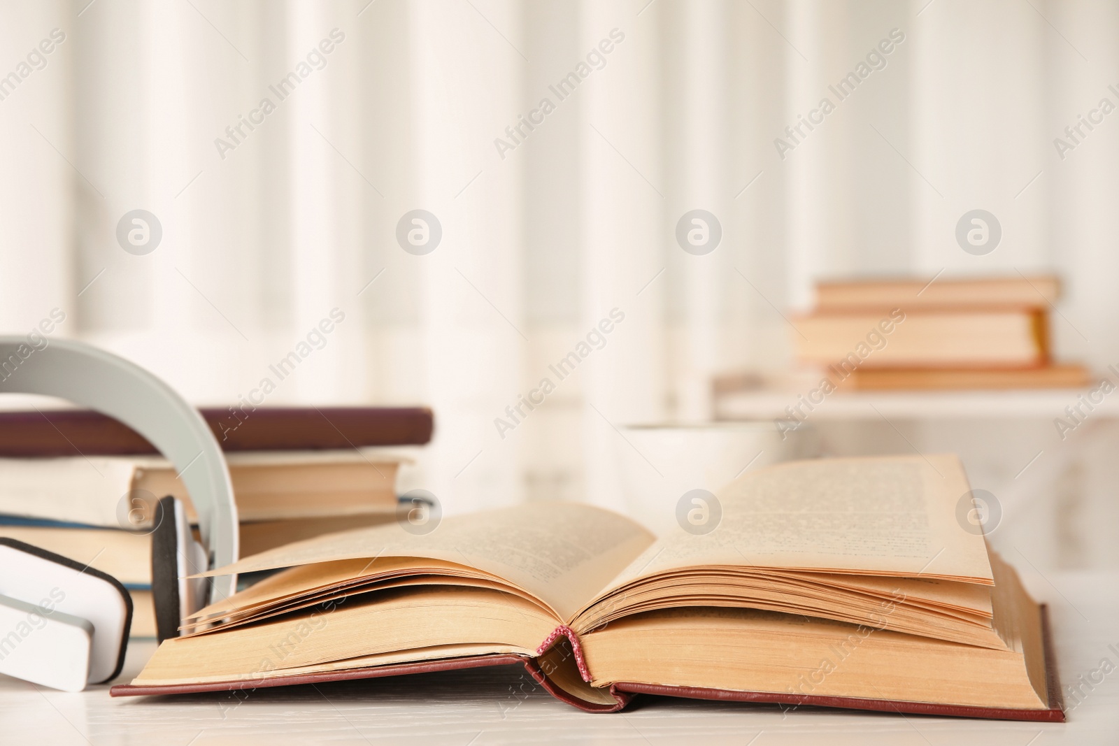 Photo of Open book and headphones on white wooden table