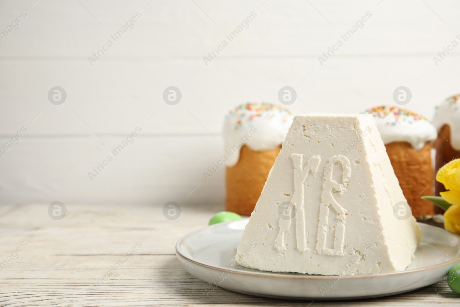 Photo of Traditional cottage cheese Easter paskha and eggs on white wooden table, space for text