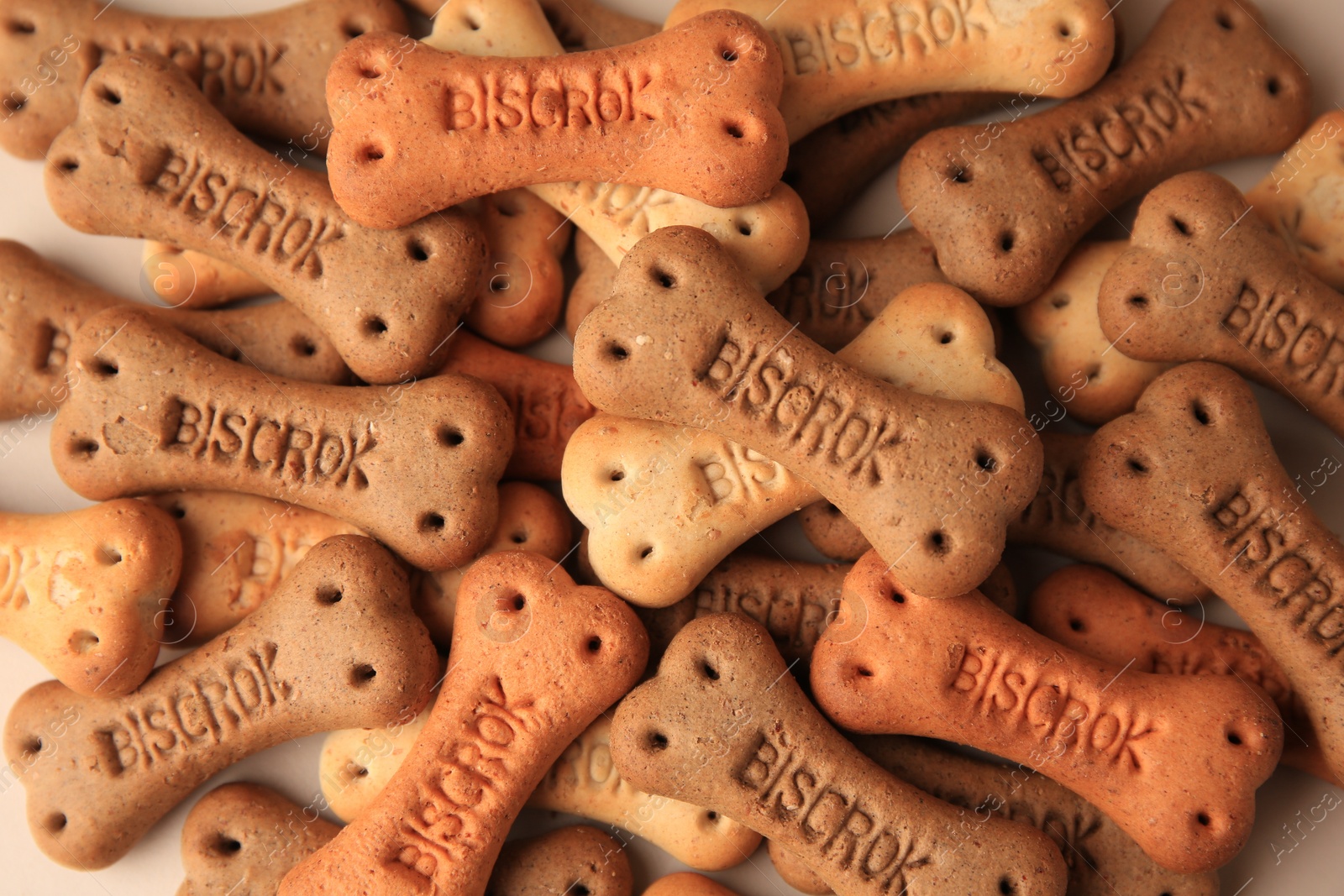 Photo of Bone shaped dog cookies on beige background, flat lay