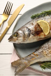 Photo of Delicious baked fish served on white wooden table, top view