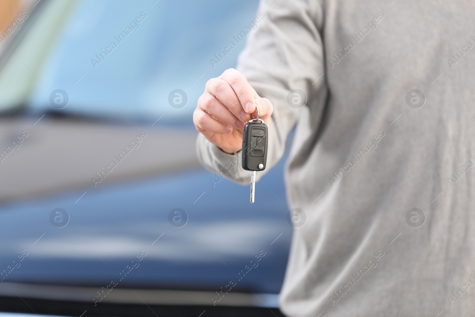 Photo of Man holding key in modern auto dealership, closeup. Buying new car