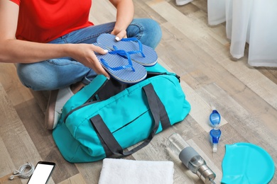 Photo of Young woman packing sports bag on floor