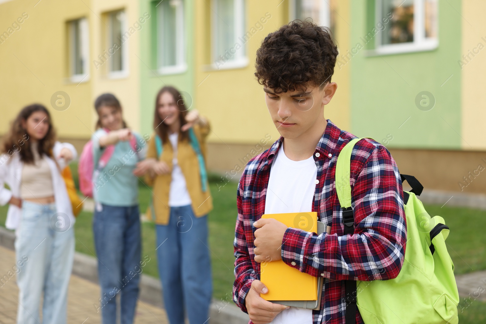 Photo of Teen problems. Group of students pointing at upset boy outdoors, selective focus