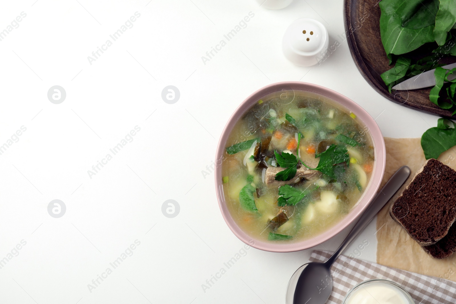 Photo of Delicious sorrel soup with meat and parsley served on white table, flat lay. Space for text