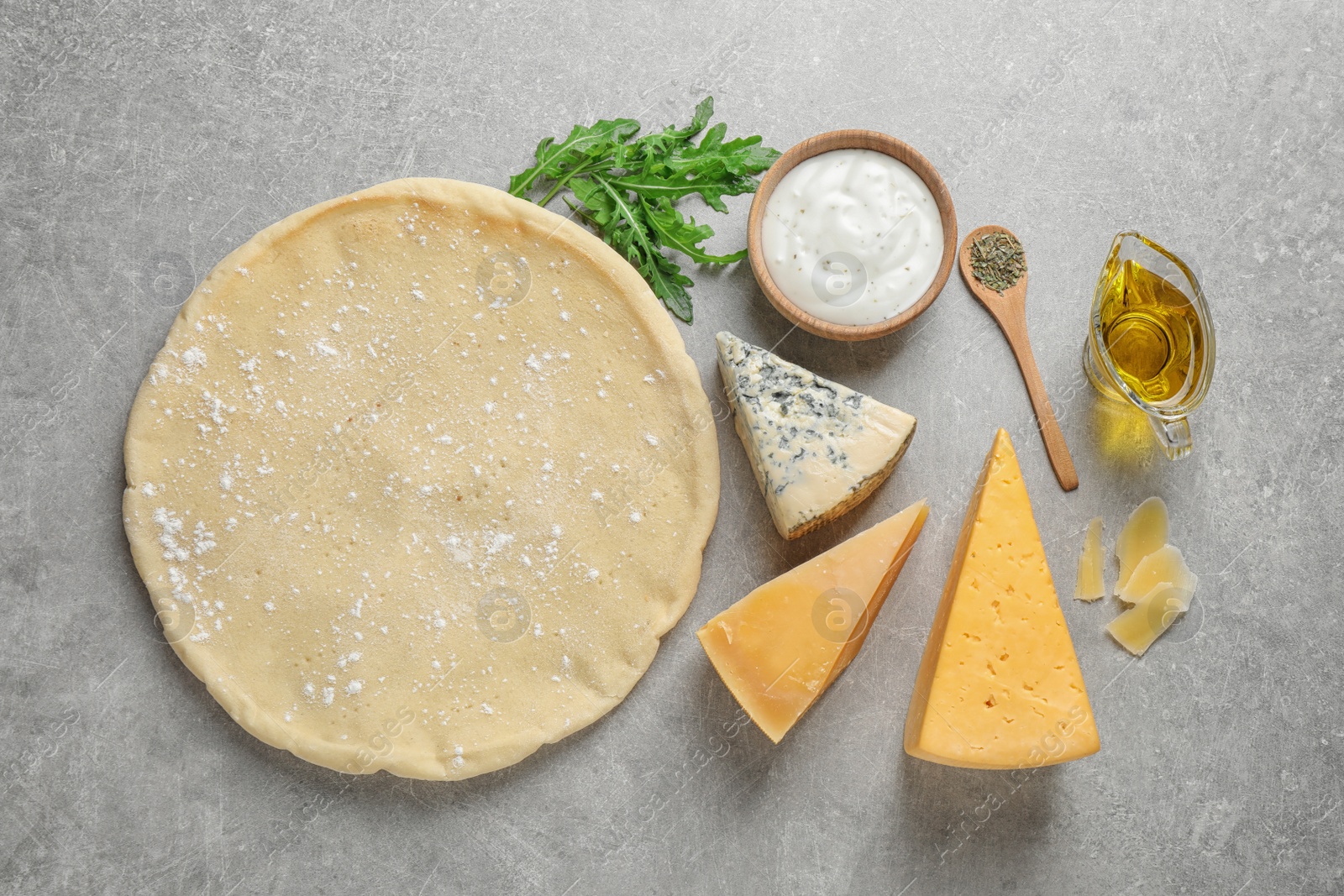 Photo of Flat lay composition with pizza crust and fresh ingredients on grey table