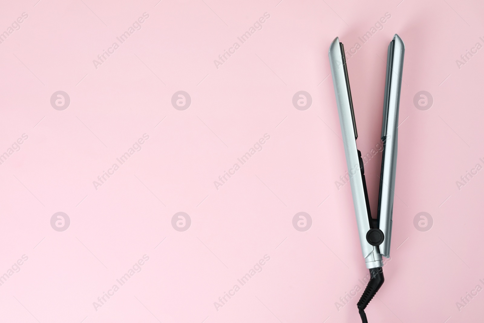 Photo of Modern hair iron for straightening on color background, top view with space for text