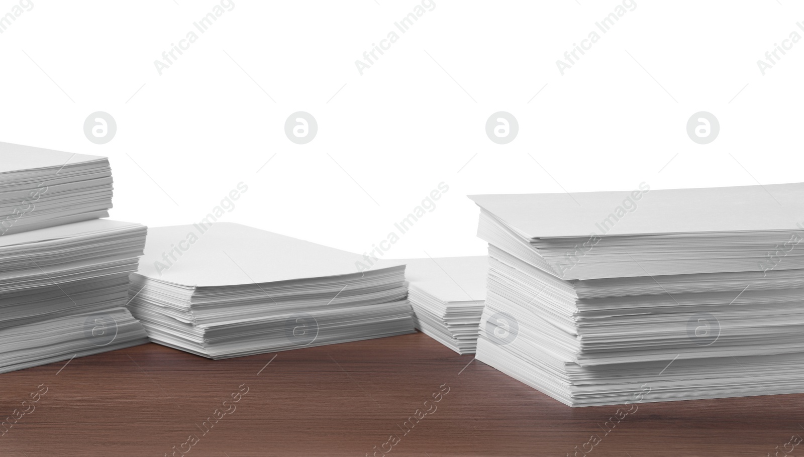 Photo of Stacks of paper sheets on wooden table against white background