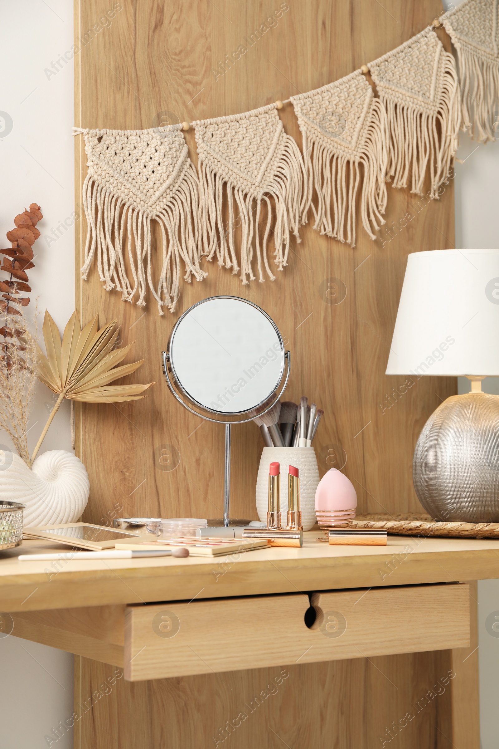 Photo of Dressing table with mirror, makeup products and decor in room