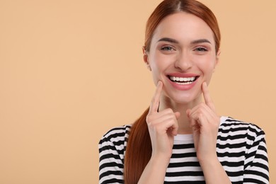 Photo of Beautiful woman showing her clean teeth and smiling on beige background, space for text