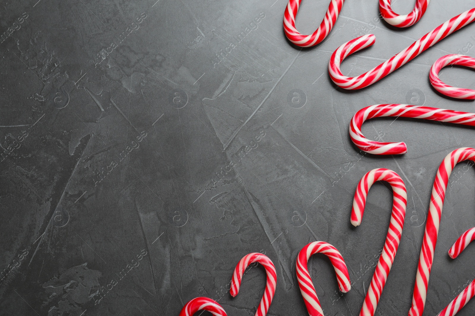 Photo of Sweet Christmas candy canes on grey background, flat lay. Space for text