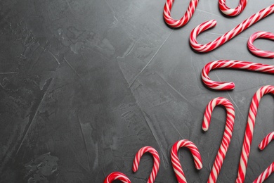 Sweet Christmas candy canes on grey background, flat lay. Space for text