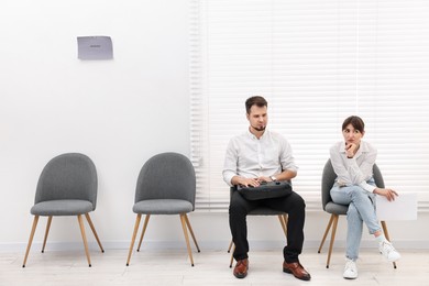 Man and woman waiting for job interview indoors