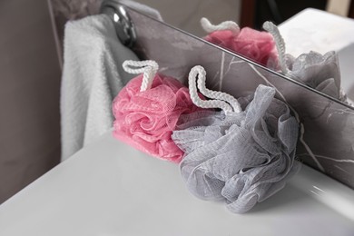 Photo of Colorful shower puffs on washbasin in bathroom