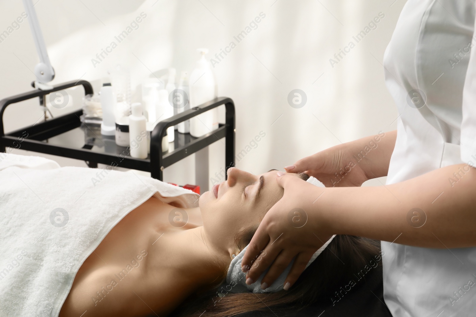 Photo of Cosmetologist making face massage to client in clinic, closeup