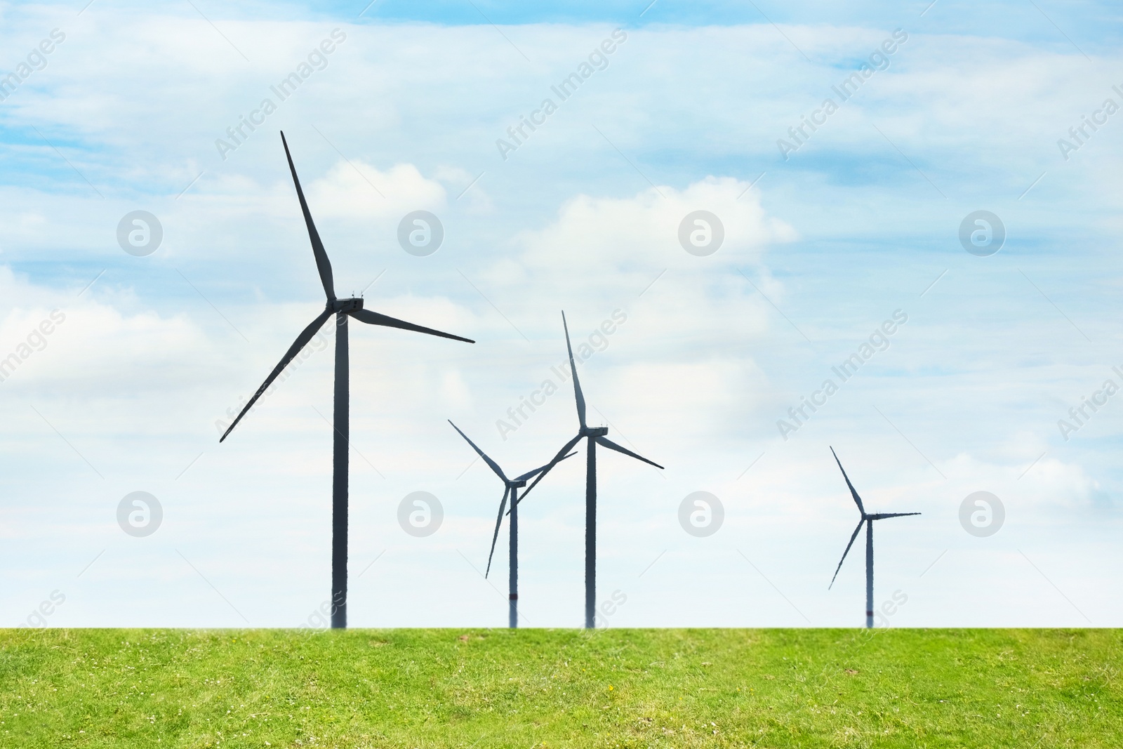 Image of Alternative energy source. Wind turbines in field under cloudy sky