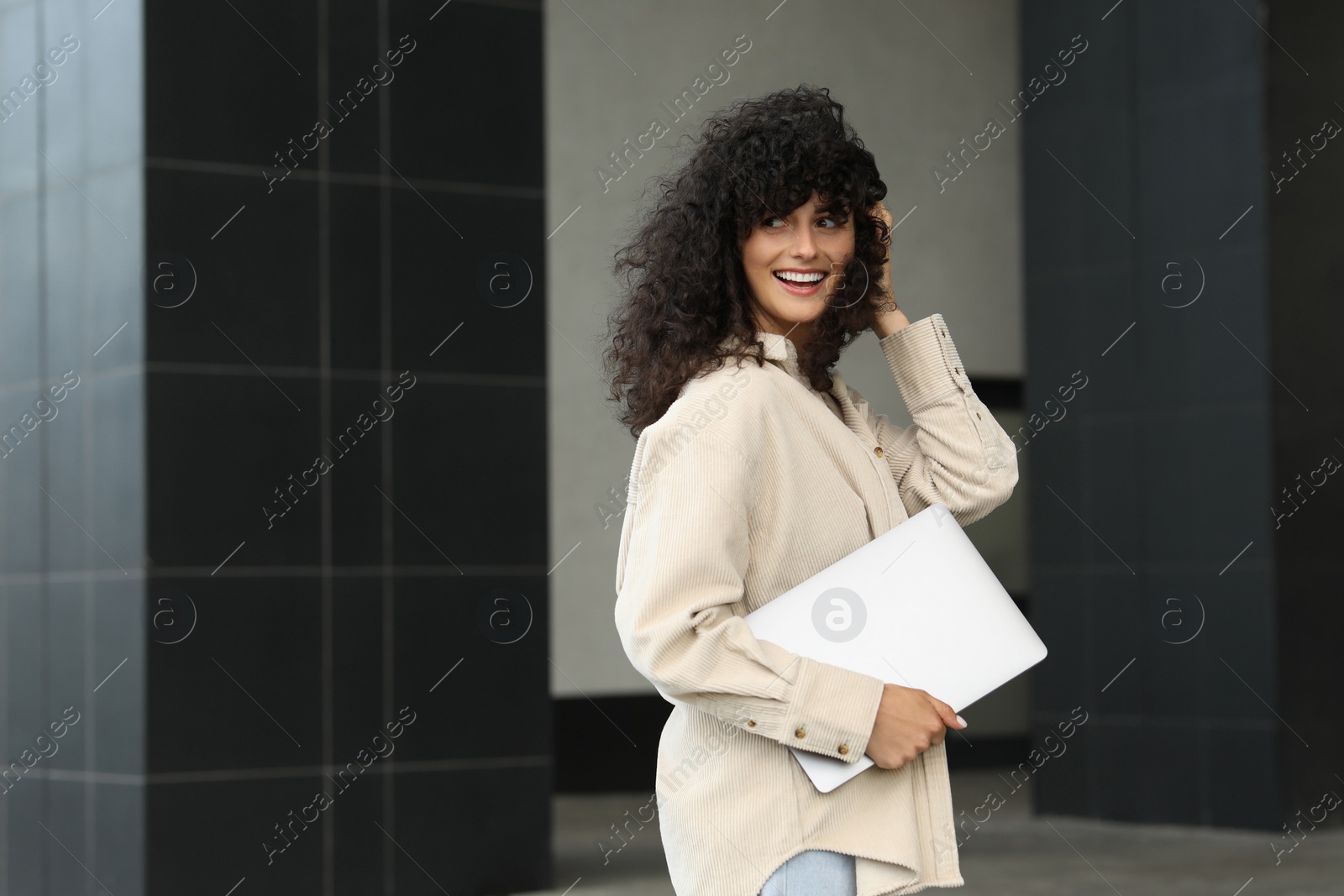 Photo of Happy young woman holding modern laptop outdoors. Space for text