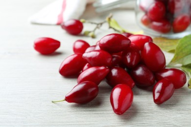 Photo of Pile of fresh ripe dogwood berries on white wooden table, closeup