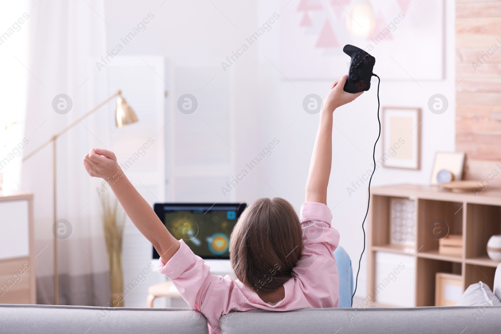 Photo of Emotional young woman playing video games at home