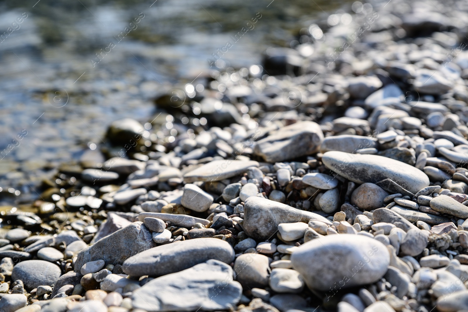 Photo of River coast with stones and pebbles on sunny day