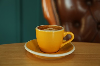 Photo of Cup of delicious coffee on wooden table indoors