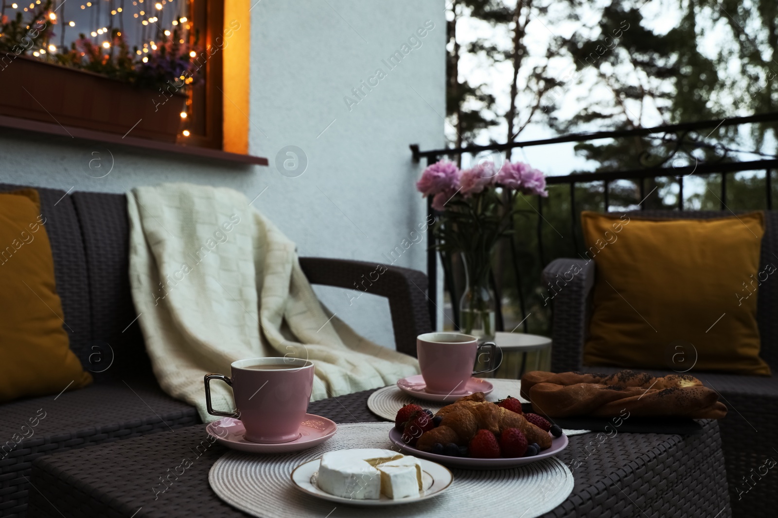 Photo of Rattan table with drink and food on outdoor terrace in evening