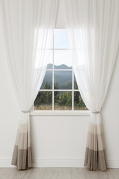 Beautiful view of mountain landscape through window with curtains