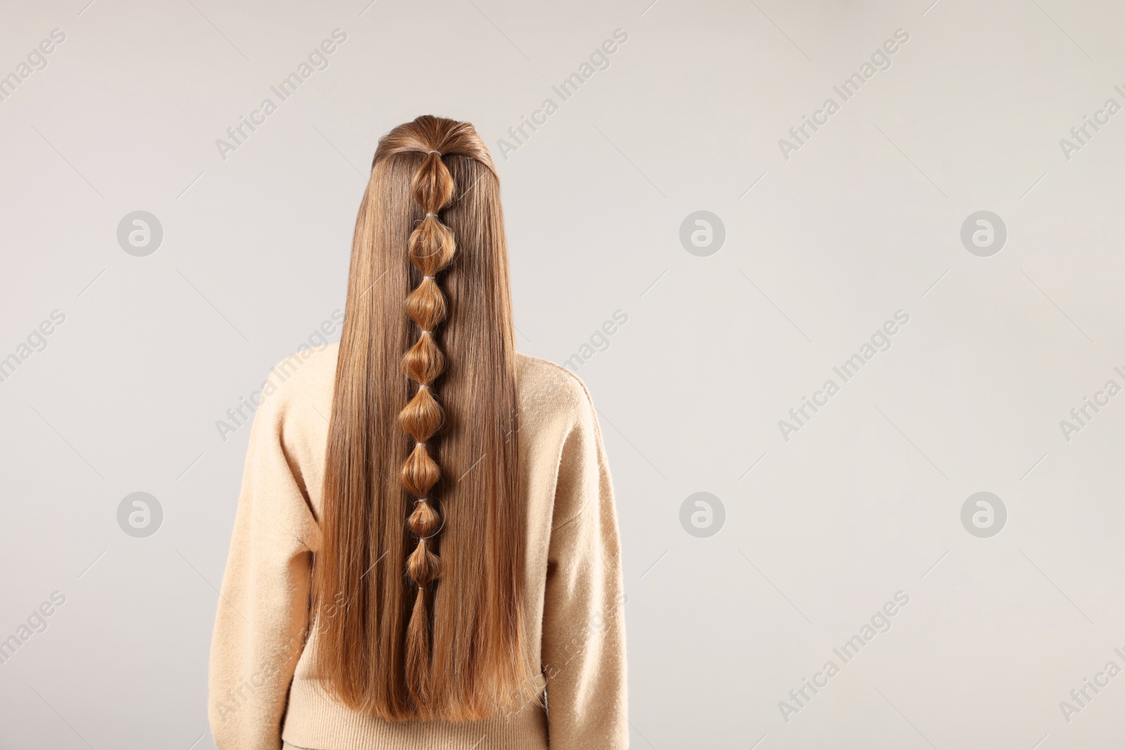 Photo of Woman with braided hair on grey background, back view. Space for text