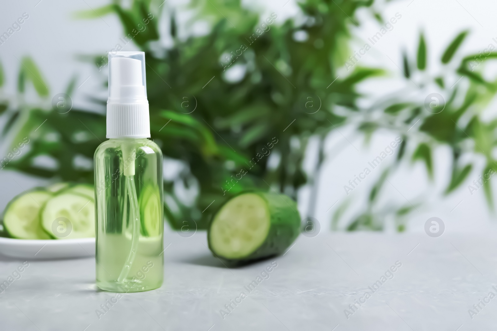 Photo of Cucumber tonic in bottle on table against blurred background. Space for text