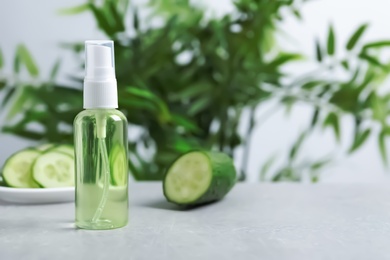 Photo of Cucumber tonic in bottle on table against blurred background. Space for text