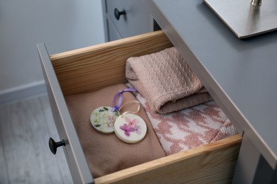 Photo of Beautiful scented wax sachets and clothes in dresser drawer indoors