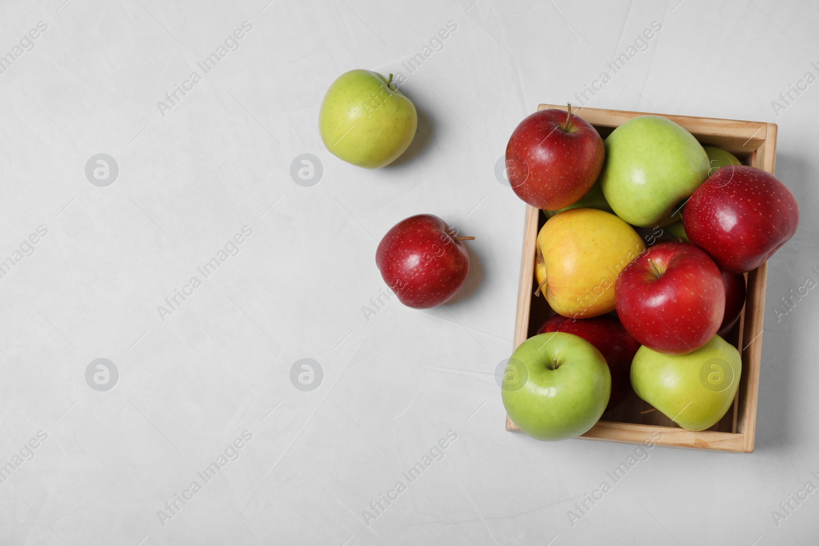 Photo of Wooden crate filled with fresh juicy apples on table, top view. Space for text