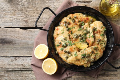 Delicious chicken piccata with herbs and lemon on wooden table, flat lay. Space for text