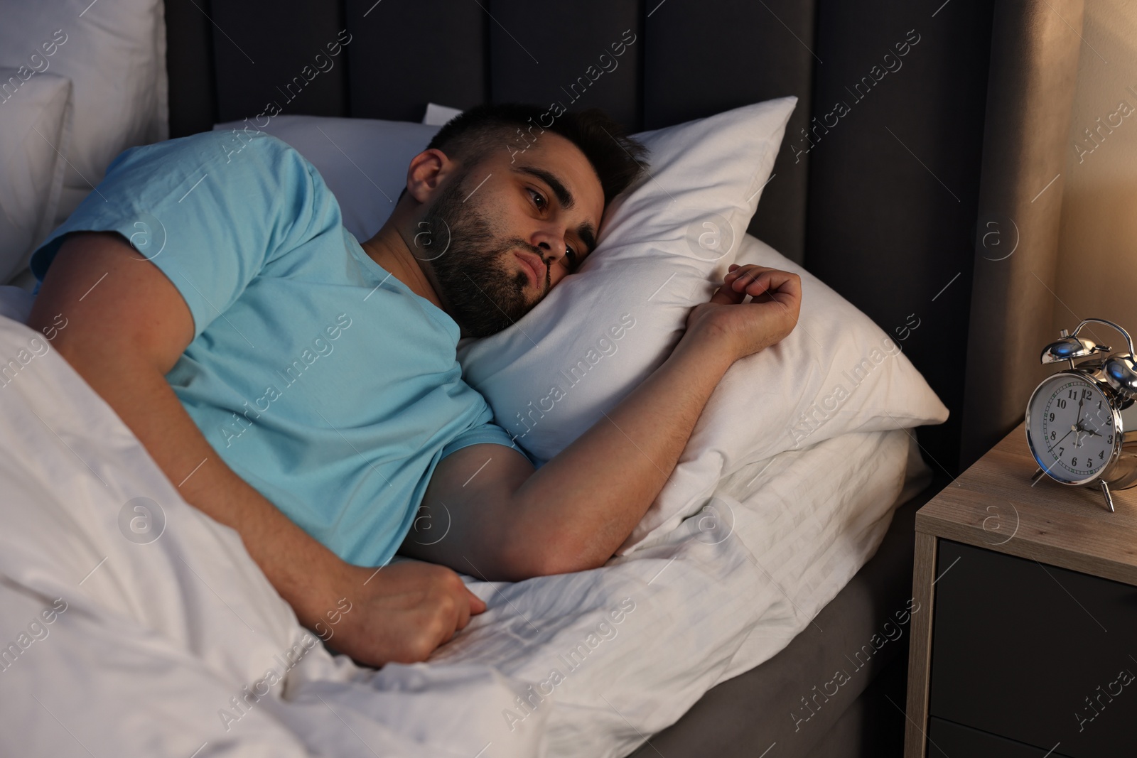 Photo of Frustrated man suffering from insomnia in bed