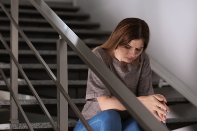 Lonely depressed woman sitting on stairs indoors