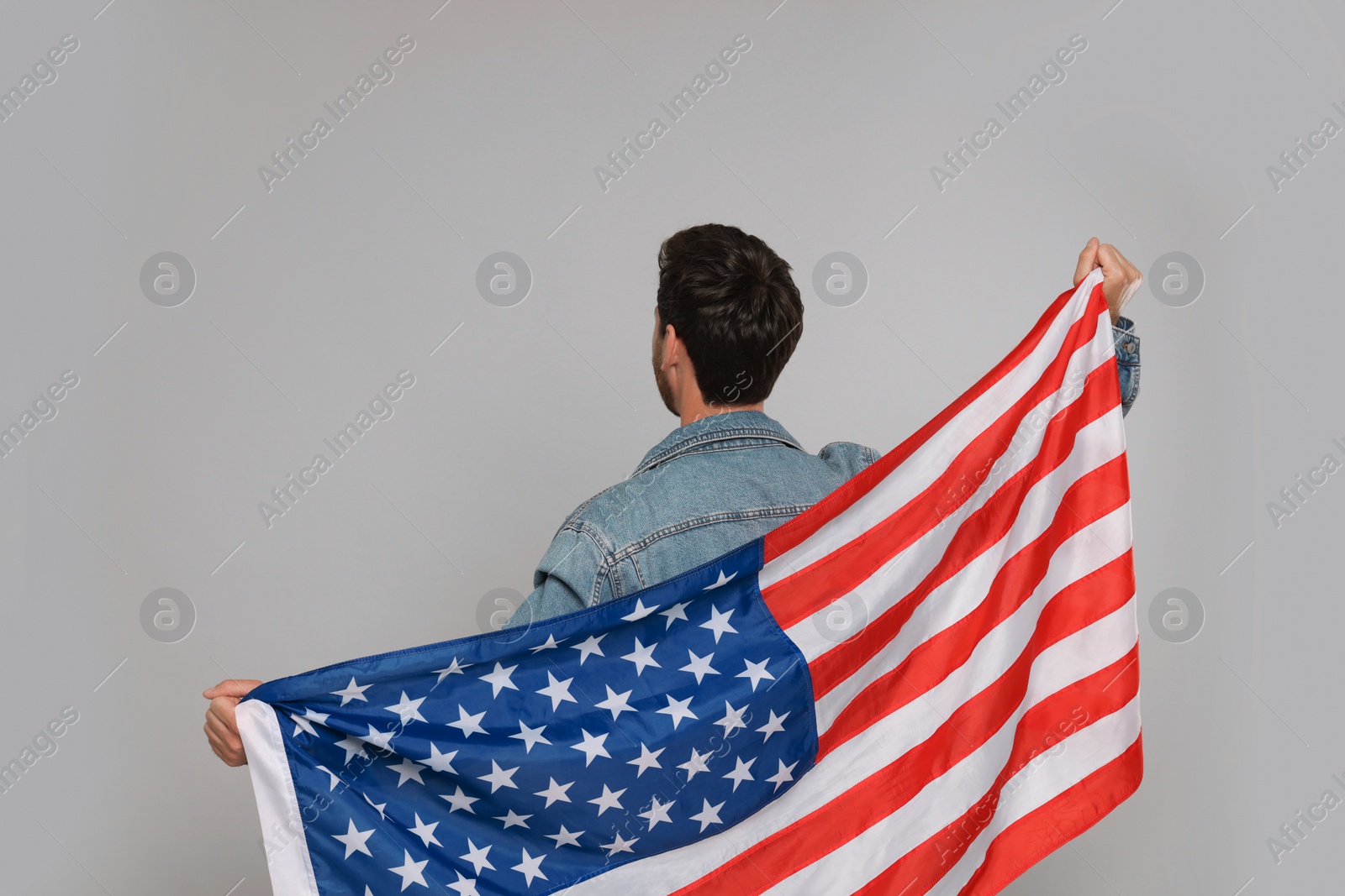 Photo of 4th of July - Independence Day of USA. Man with American flag on grey background, back view