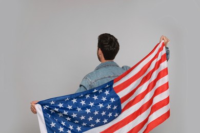 Photo of 4th of July - Independence Day of USA. Man with American flag on grey background, back view
