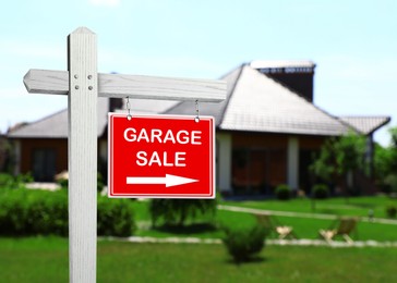 Image of Sign with text GARAGE SALE and blurred view of modern house on sunny day
