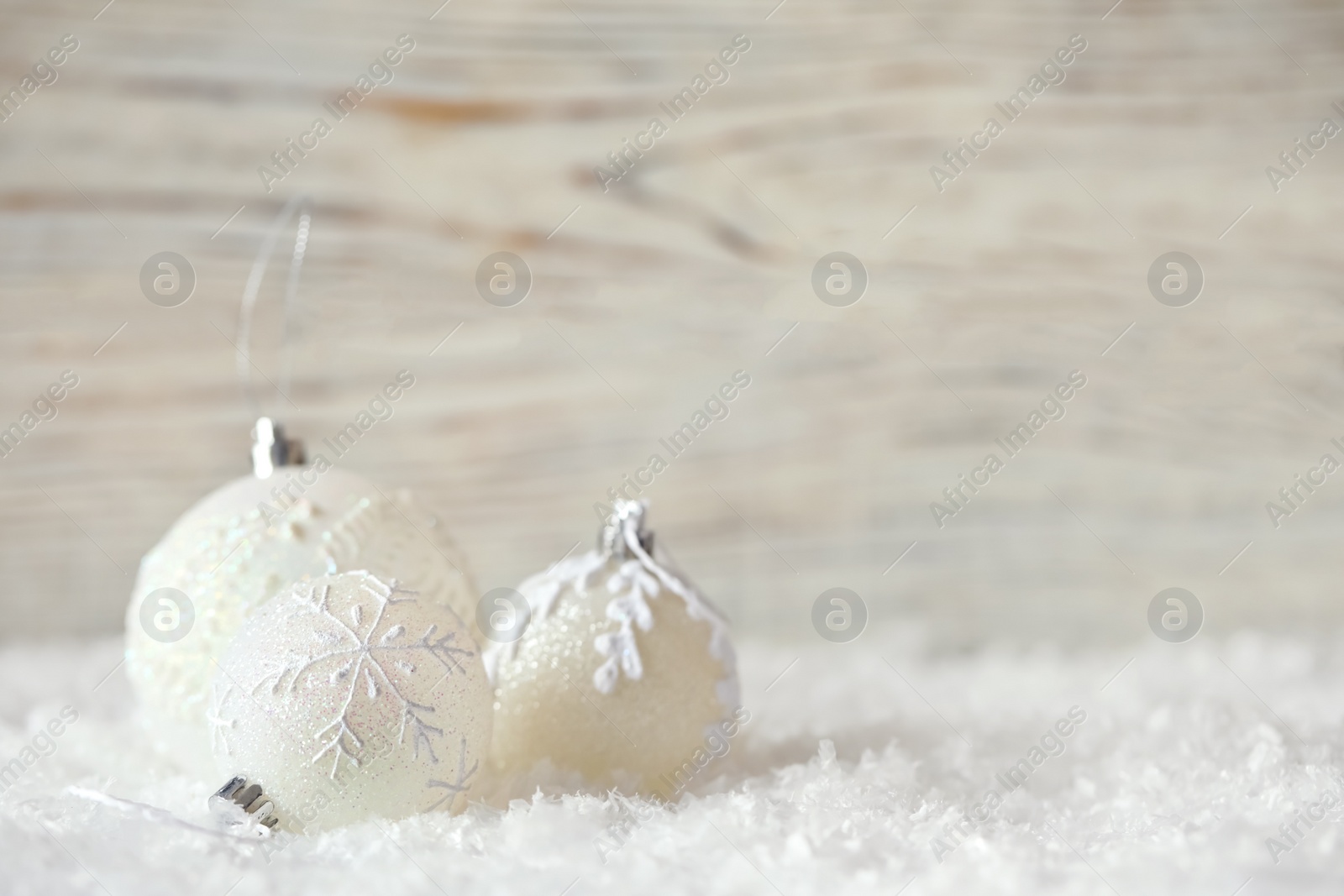 Photo of Beautiful Christmas balls on snow against blurred background. Space for text