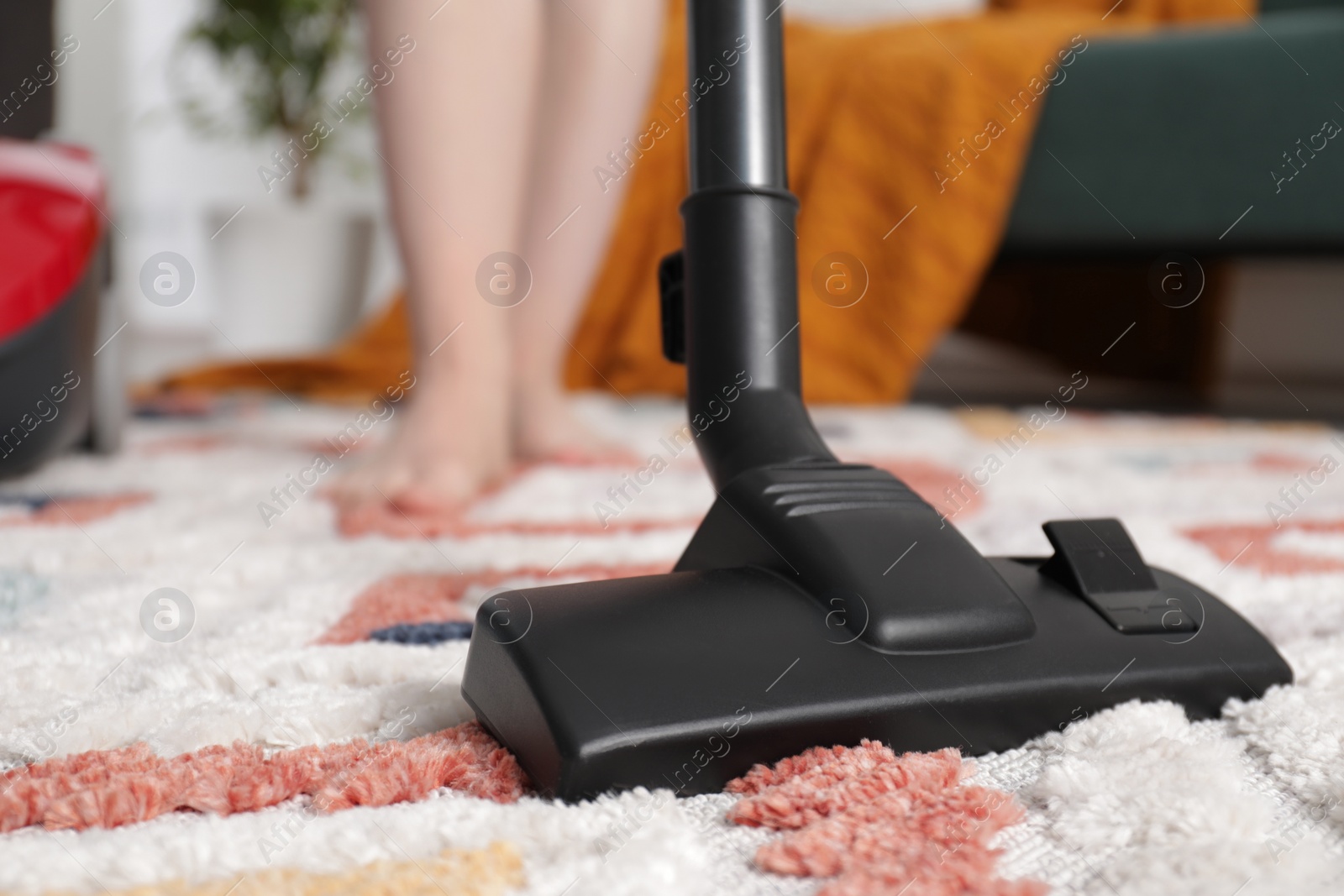 Photo of Woman cleaning carpet with vacuum cleaner at home, closeup. Space for text