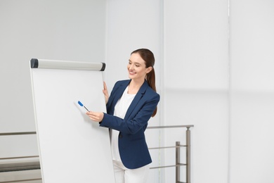 Professional business trainer near flip chart board indoors. Space for text