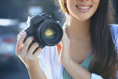 Image of Young photographer with professional camera outdoors, closeup