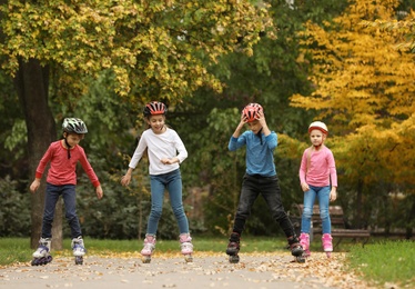 Happy children roller skating in autumn park