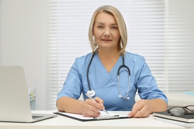 Photo of Doctor writing at white table in clinic