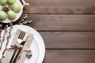 Photo of Festive Easter table setting with eggs on wooden background, flat lay. Space for text