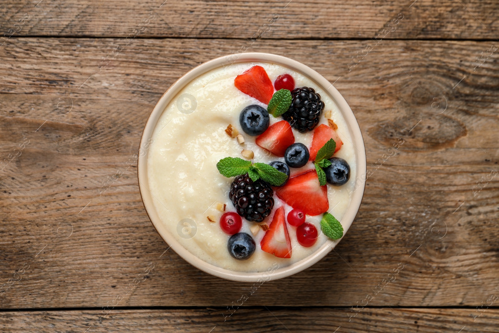 Photo of Delicious semolina pudding with berries on wooden table, top view