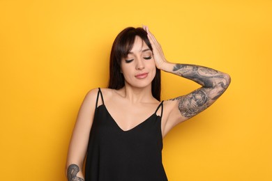 Photo of Beautiful woman with tattoos on arms against yellow background