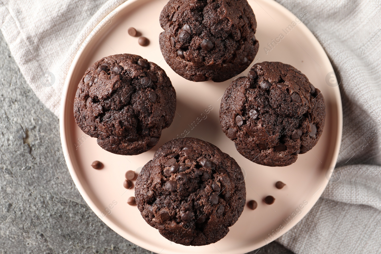 Photo of Delicious chocolate muffins on grey textured table, top view