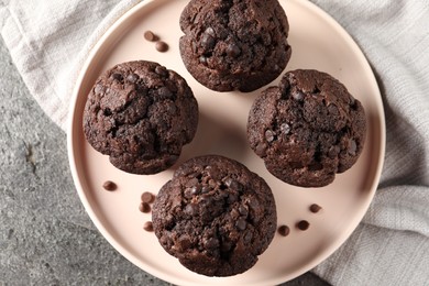 Delicious chocolate muffins on grey textured table, top view